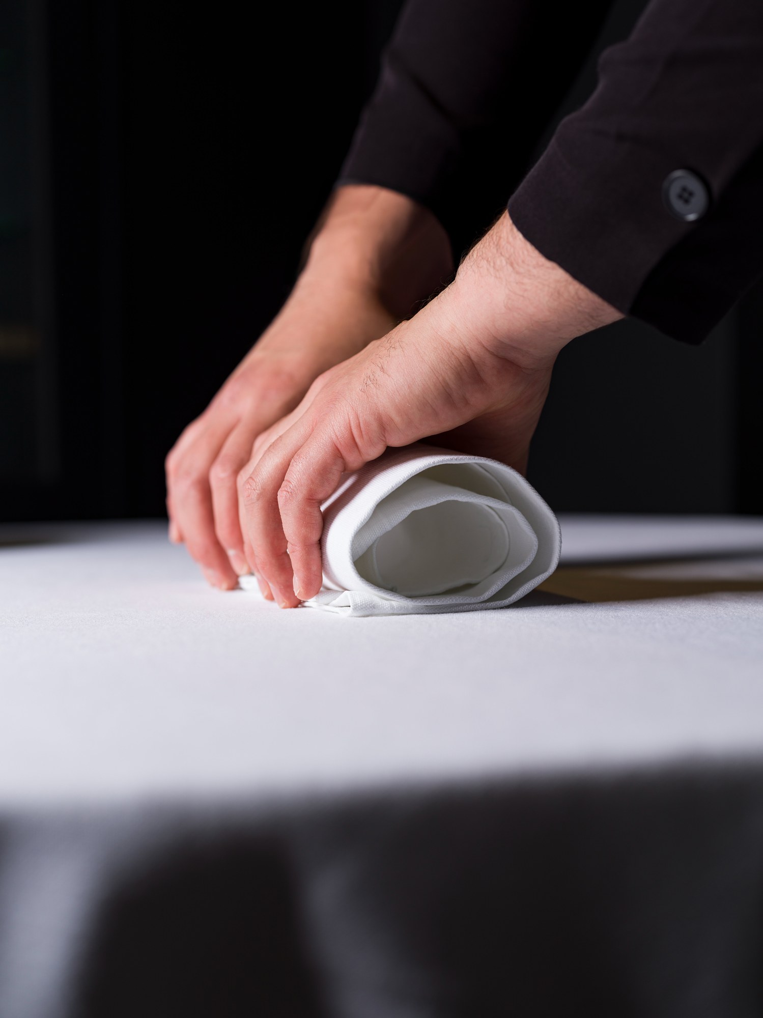 Le mani preparano il tovagliolo, un gesto del rito della tavola